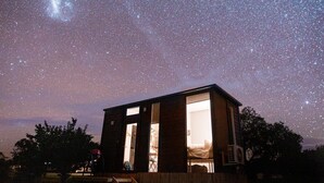 A small, modern building with large windows, under a starry night sky. - Tiny Balloon House by Tiny Away (Canowindra)