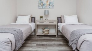 A twin bedroom with two beds, a nightstand, a lamp, and a painting on the wall. - OSU 6D · Newly Renovated (6D) OSU/Central ❤Near EVERYTHING (Columbus)