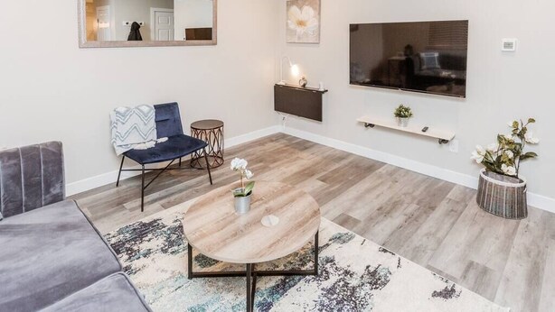 A modern living room with a sofa, a round coffee table, a chair, a TV, and a mirror. - OSU 6D · Newly Renovated (6D) OSU/Central ❤Near EVERYTHING (Columbus)