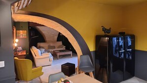 A cozy living room with a sofa, chairs, a dining table with fruit, and a kitchen area with a refrigerator and a rooster decoration. - Mas " La Maison de mon Père " Avignon à 10 Minutes, Village de Pujaut 30131 (Pujaut)