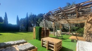 A garden with a wooden pergola, a wooden table, and a sofa with patterned cushions. - Mas " La Maison de mon Père " Avignon à 10 Minutes, Village de Pujaut 30131 (Pujaut)