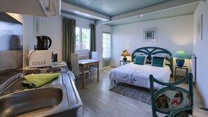 Habitación de hotel con cama, escritorio y kitchenette.