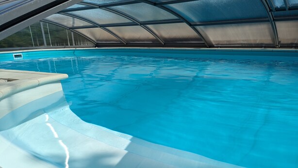 Una piscina con borde curvo y zona cubierta.