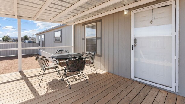 A covered patio with a table and chairs, a white door, and a view of a neighboring house. - The Villa - Amazingly Comfortable King Beds (Alpine)