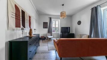 Ein modernes Schlafzimmer mit Bett, Schminktisch, Fernseher und Bildern an der Wand.