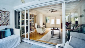 A spacious living area with a sliding glass door leading to a library, a comfortable seating area, and a ceiling fan. - Tropical Paradise, walking distance to the beach and heated pool! (Hollywood)