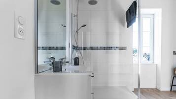 Un baño moderno con un espejo grande, una ducha y un lavamanos.