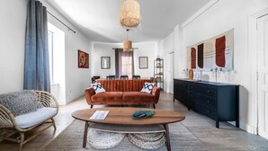 A modern living room with a sofa, coffee table, and a hanging light fixture. - Grande Maison Design, jardin, patio et parking (Gannat)
