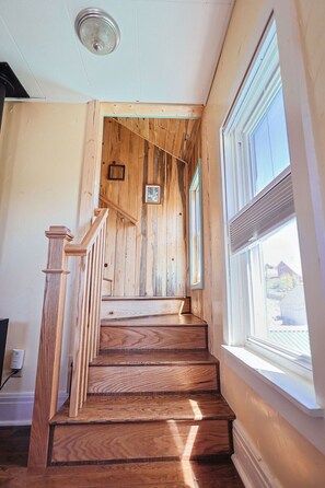 A wooden staircase leading to a landing with a framed picture and a window with a view of the outside. - Minutes from skiing and hiking (Centennial)