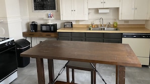 Una cucina con mobili bianchi, un tavolo di legno, un forno a microonde, un tostapane e un lavello.
