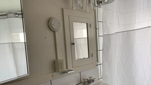 Un bagno con un lavandino bianco, uno specchio e una tenda da doccia.
