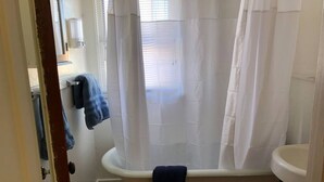 Un bagno con una vasca da bagno a piedi di leone, un lavandino bianco e una tenda da doccia.