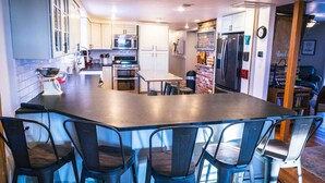 Een moderne keuken met een groot eiland, roestvrijstalen apparatuur en een geaccentueerde bakstenen muur.
