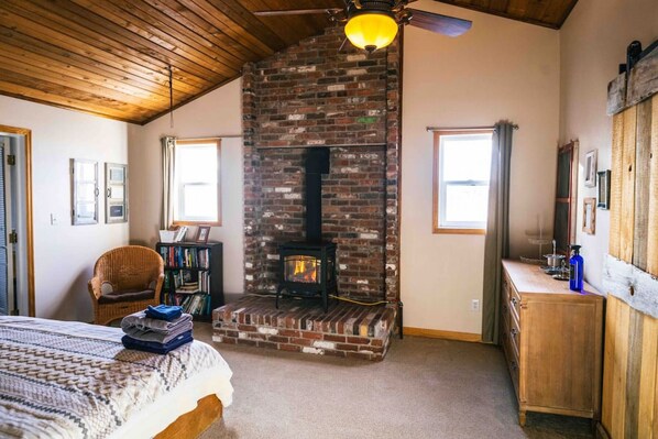 A cozy room with a brick fireplace, a bed, a bookshelf, and a wooden dresser. - Close to town, room to spread out: Sleeps 9 in 5 bedrooms (Cheyenne)