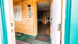 Un interior de madera con un cartel de bienvenida, una puerta que da a una habitación y un reloj a la vista.
