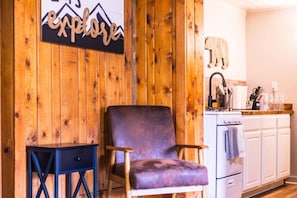 A wooden interior with a chair, a small table, and a kitchen area with cabinets and a sink. - Centennial stay perfect for families! (Centennial)