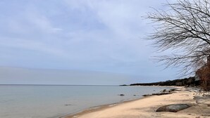 A beach with clear water, a sandy shore, and large rocks.