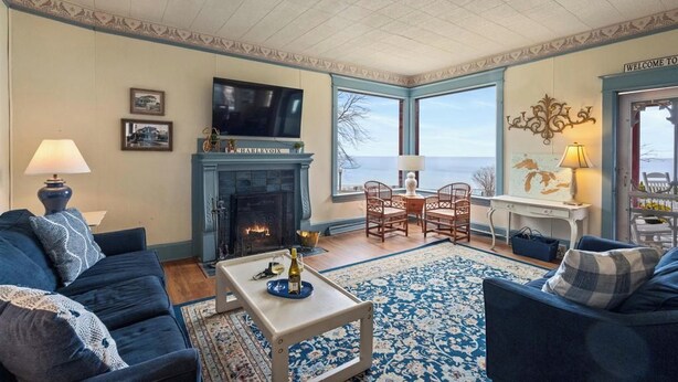 A living room with a fireplace, a television, and a view of the sea.