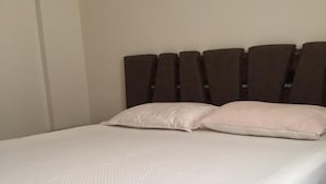 A bed with a white bedspread and two pillows, a dark headboard, and a plain wall. - Beachside House in Gundogan (Bodrum)