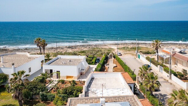 A coastal residential area with white buildings, a beach, and a clear blue sky. - VILLA SUNSET - Villa facing the sea (Torre Suda)
