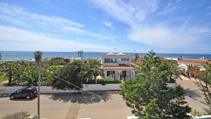 A coastal residential area with a house featuring a tiled roof, a view of the sea, and a parking area with a car. - VILLA SUNSET - Villa facing the sea (Torre Suda)