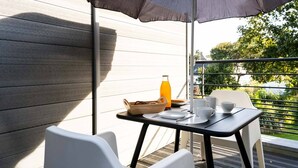 A balcony with a table set for breakfast, including a bottle of orange juice, a bowl of bread, and cups. - Au NEUF MILLE, luxury studio **** 2 steps from the port of Perros-Guirec (Perros-Guirec)