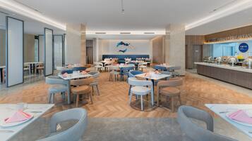 Un comedor moderno con varias mesas y sillas, un mostrador de buffet y un adorno mural.