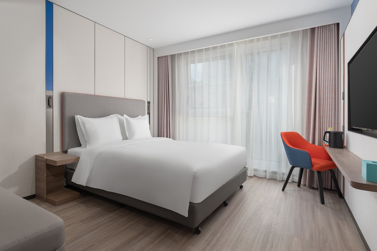 A hotel room with a bed, a desk, and a chair.