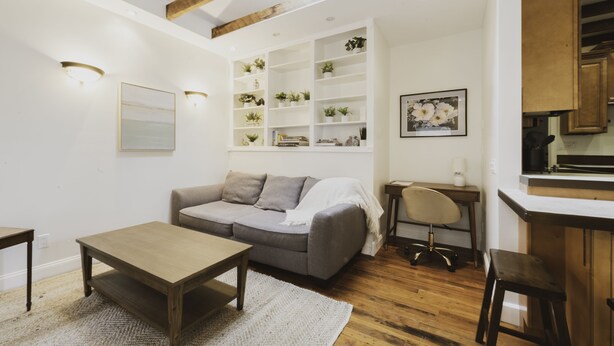 A living room with a sofa, coffee table, and built-in shelving with plants. - Cozy Carriage House w/ Courtyard View ★ Victorian District ★ Near Forsyth Park
 (Savannah)