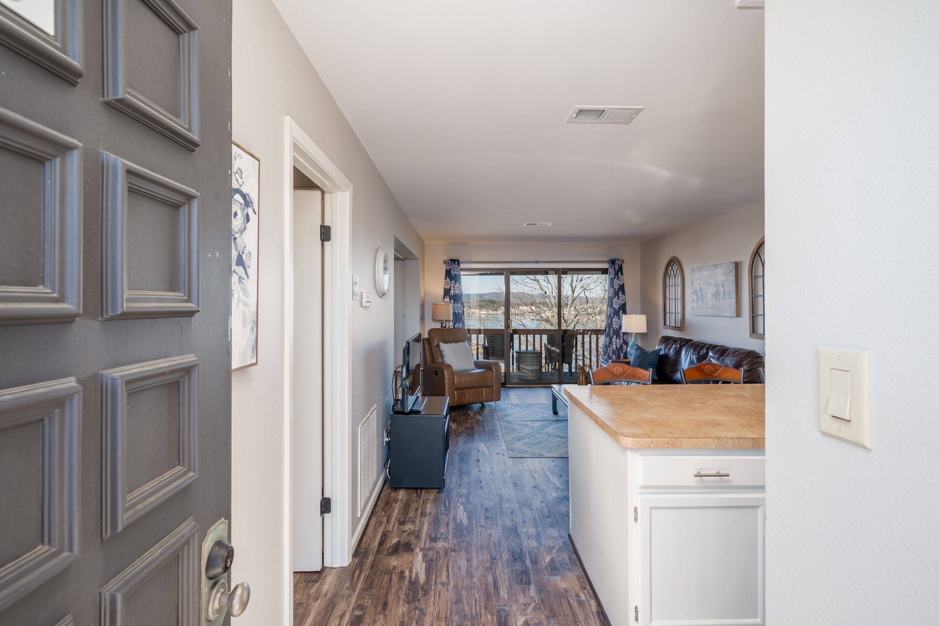 Ein Flur mit Holzboden, der in einen Wohnbereich mit einer Couch und einem Fernseher führt.
