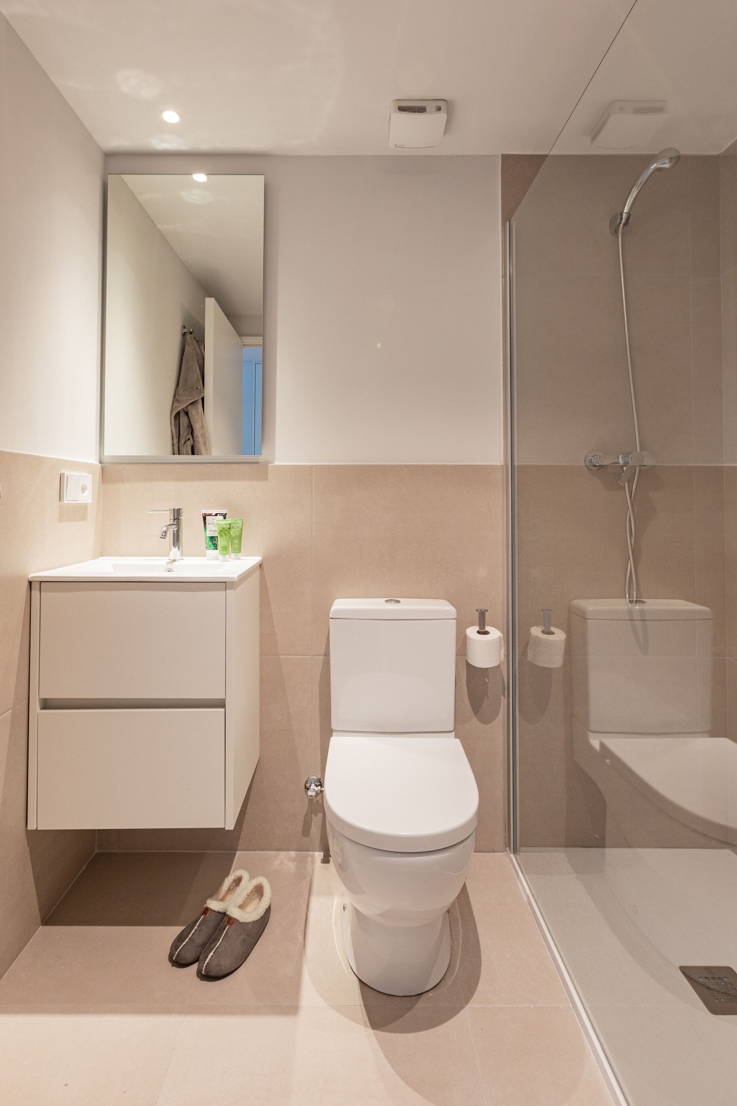 Un baño moderno con inodoro, lavamanos y ducha.