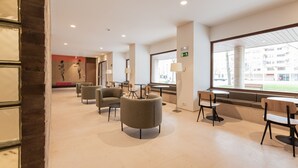 A modern hotel lobby with seating areas, tables, and large windows offering views of the outside. - Micampus Pamplona  (Pamplona)