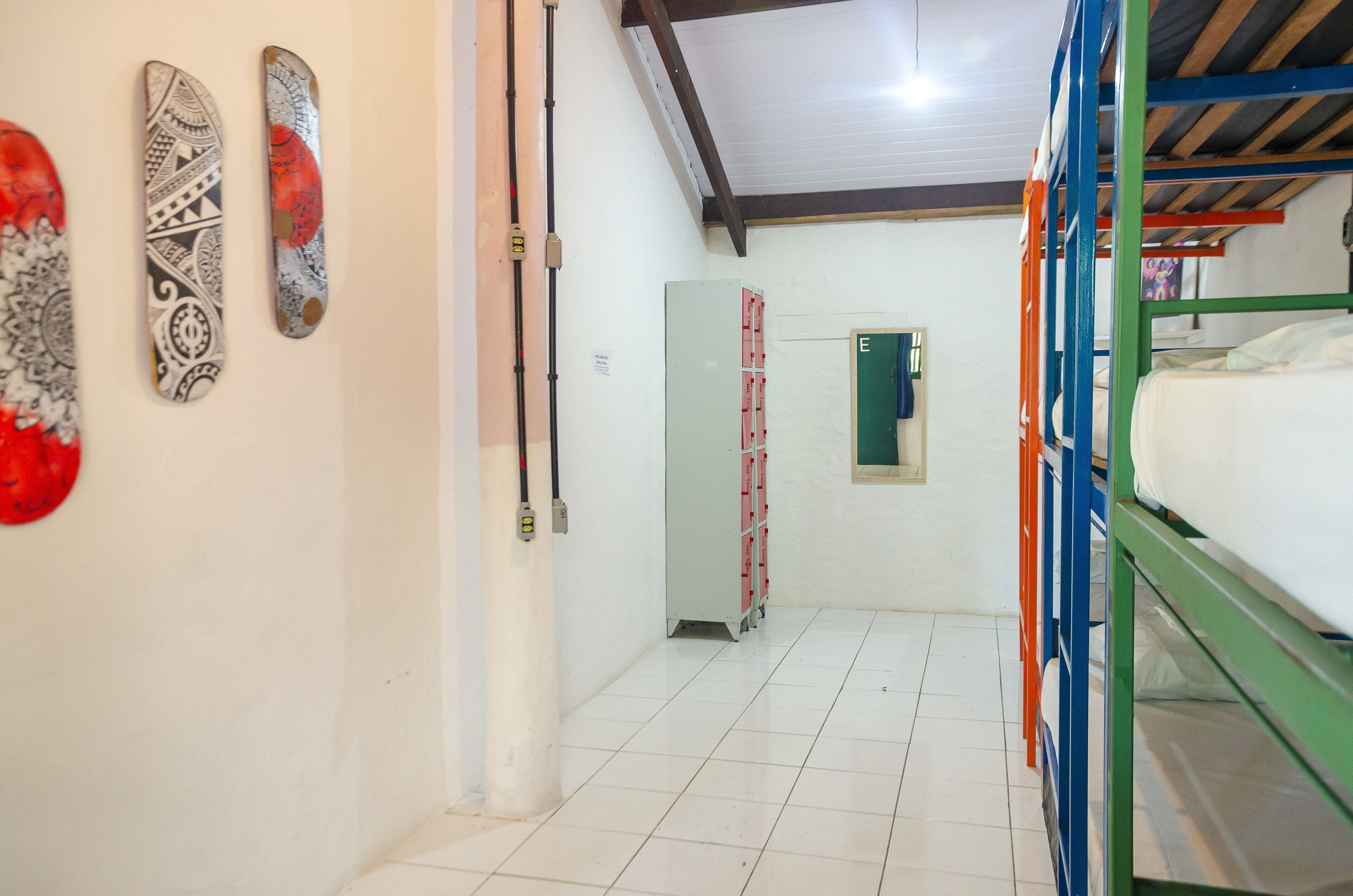 A narrow hallway with bunk beds on the right, a white door with a green sign, and a ladder against the wall.