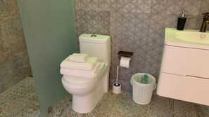 Un baño con inodoro, lavamanos y cubo de basura.