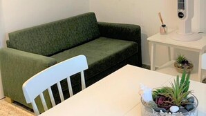 Uma sala de estar moderna com um sofá verde, mesa branca e uma luminária pendente.
