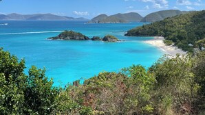 Een kustlandschap met helder turquoise water, kleine eilandjes en een strandgebied.
