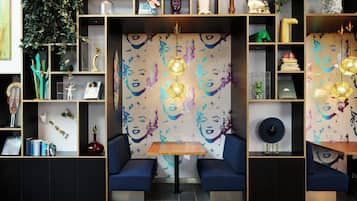 Un interior moderno con una zona de estar central, estanterías con diversos objetos decorativos y una pared con un diseño de rostros.