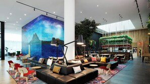 A spacious lobby with a large mural, modern seating, and a bar area.