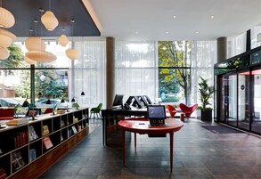 Una biblioteca moderna con estanterías, una computadora y una mesa roja.