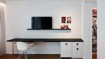 Una habitación moderna con un escritorio negro, una silla blanca y un televisor montado.