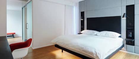A modern bedroom with a bed, a desk, and a chair.