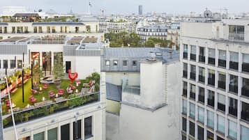 Een hoog gebouw met meerdere verdiepingen, grote ramen en een dakterras met terrasmeubilair.