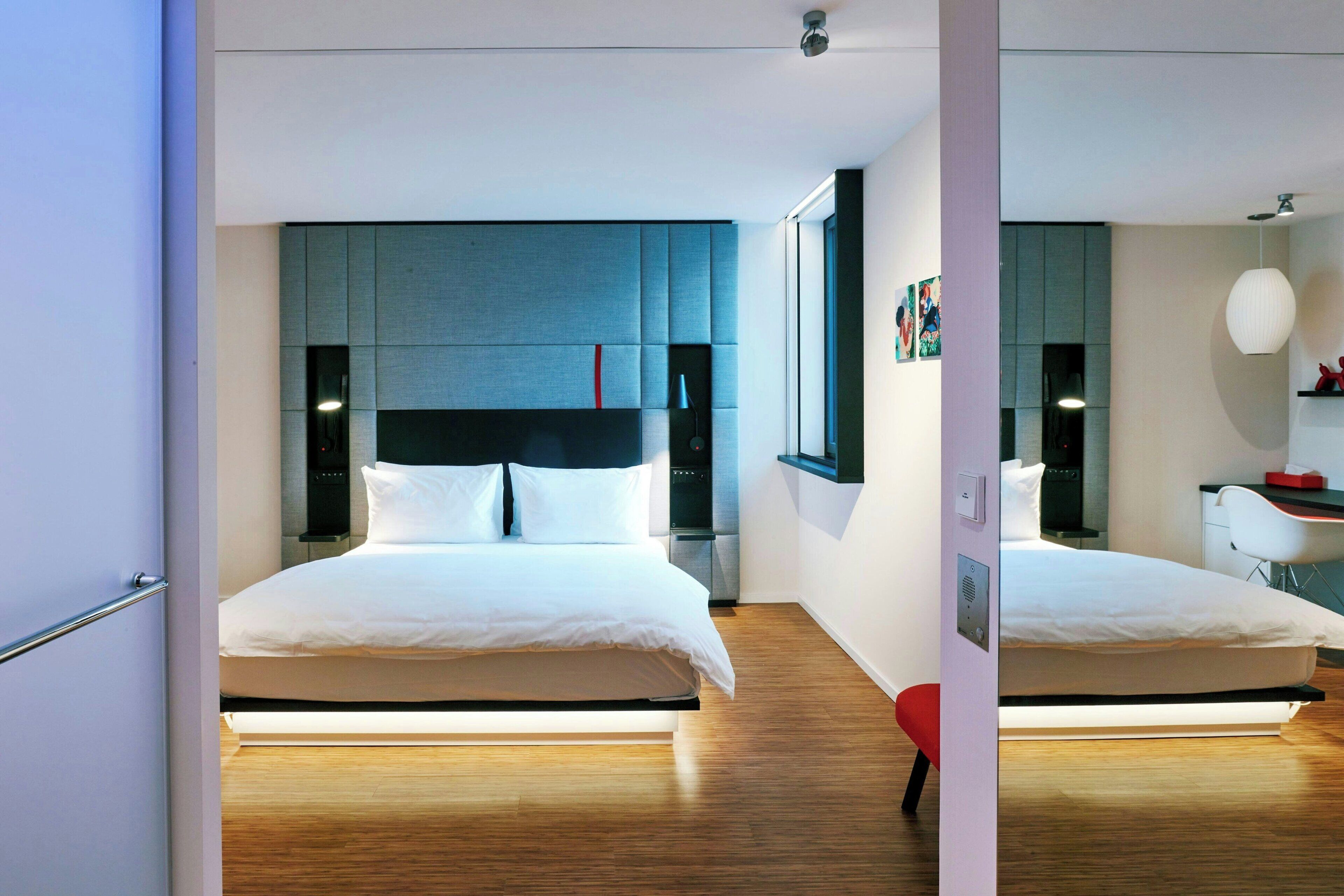 Quarto de hotel moderno com uma cama grande, uma mesa e uma cadeira.