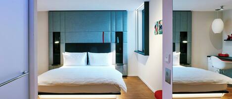 Quarto de hotel moderno com uma cama grande, uma mesa e uma cadeira.