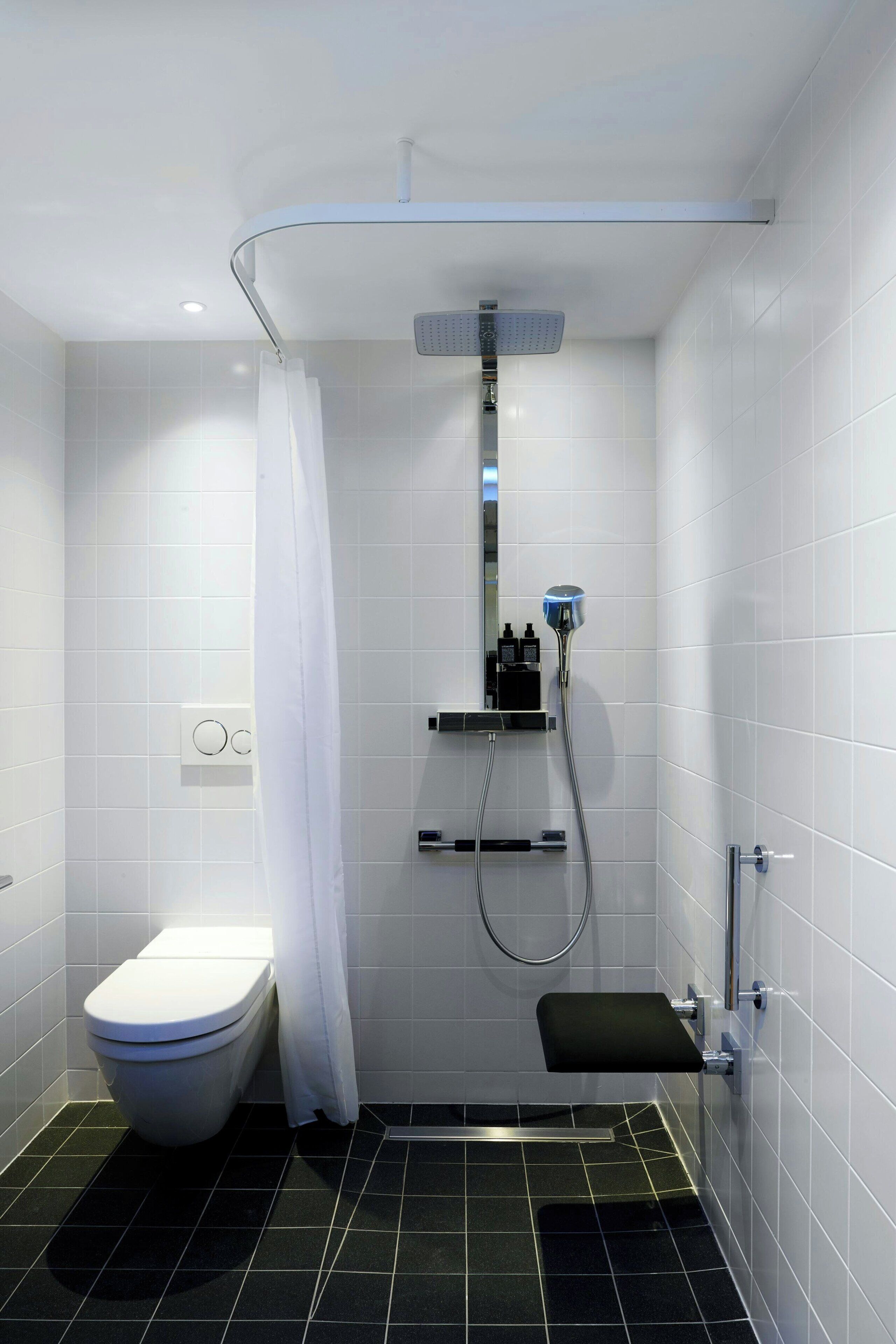Een moderne badkamer met een douche, toilet en een bankje.