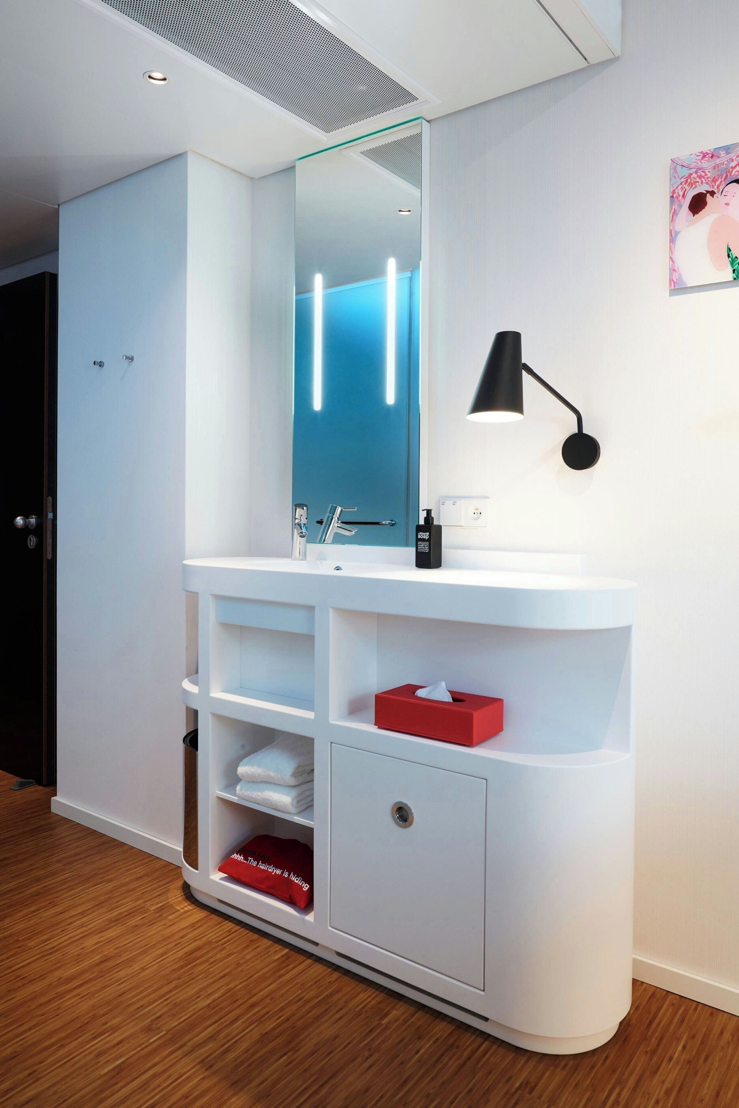 A modern bathroom with a white vanity, a mirror, a black wall-mounted lamp, and a towel rack.