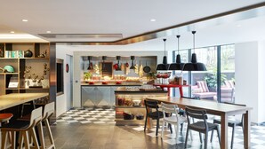 A modern kitchen with a checkered floor, a dining area with chairs, and a view of the outdoors. - citizenM Paris Champs-Élysées (Paris)