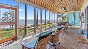 Un espace extérieur abrité, doté de chaises en osier et offrant une vue sur la plage.