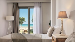 Una habitación de hotel con una cama, una mesita de noche, una lámpara y vistas a la playa.