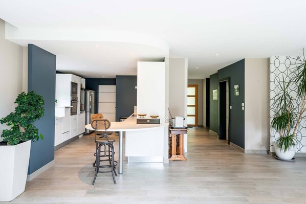 Een moderne keuken met witte kastjes, een centraal eiland en een eetgedeelte met een stoel.
